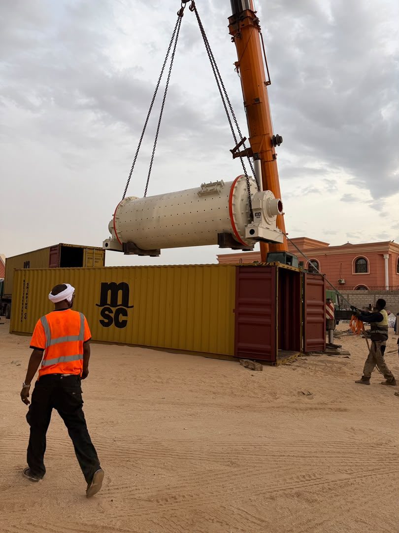 Ball mill lifted by crane beside a shipping container